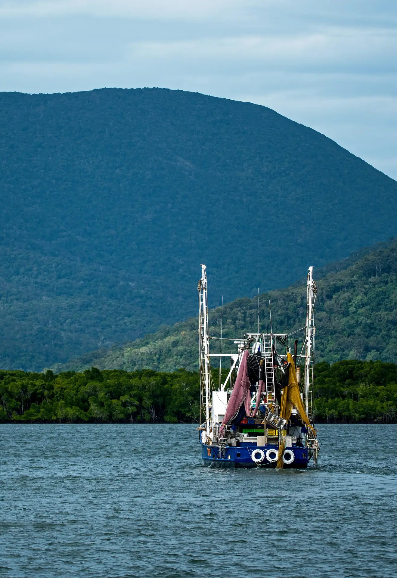 Fishing boat at sea with tall hills in the background