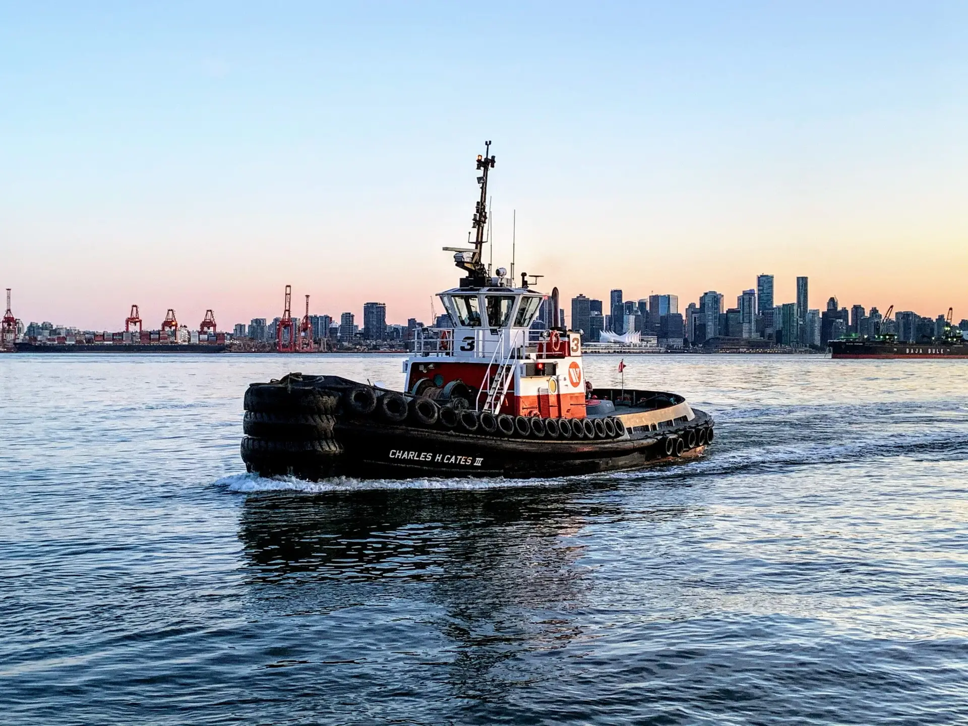 Small tug boat with a city scape in the background