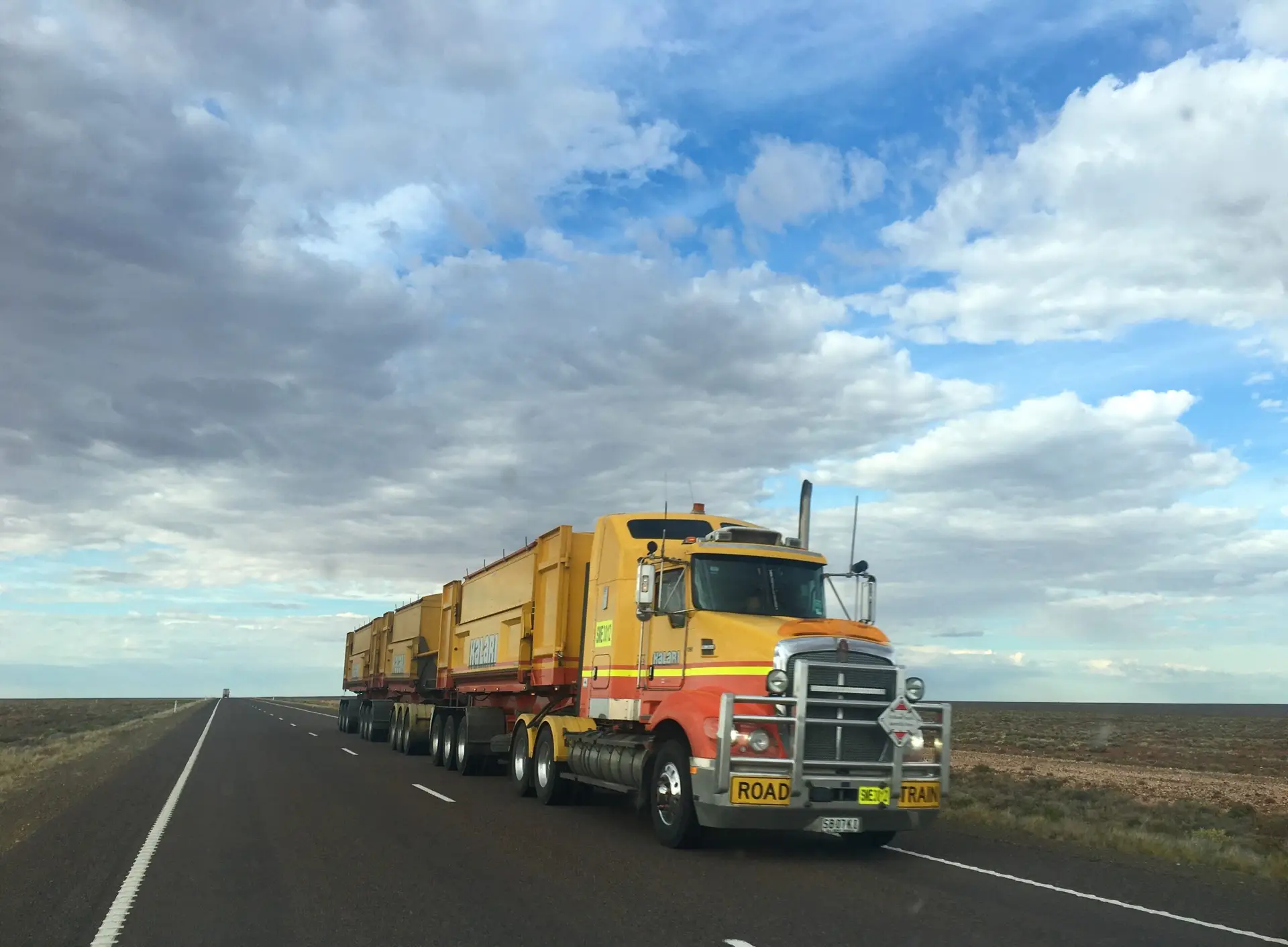 A single orange truck driving along a highway