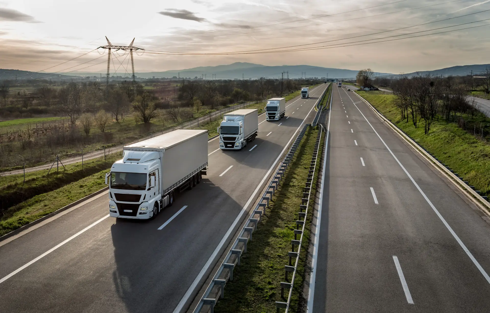 Four trucks driving in a line on a highway